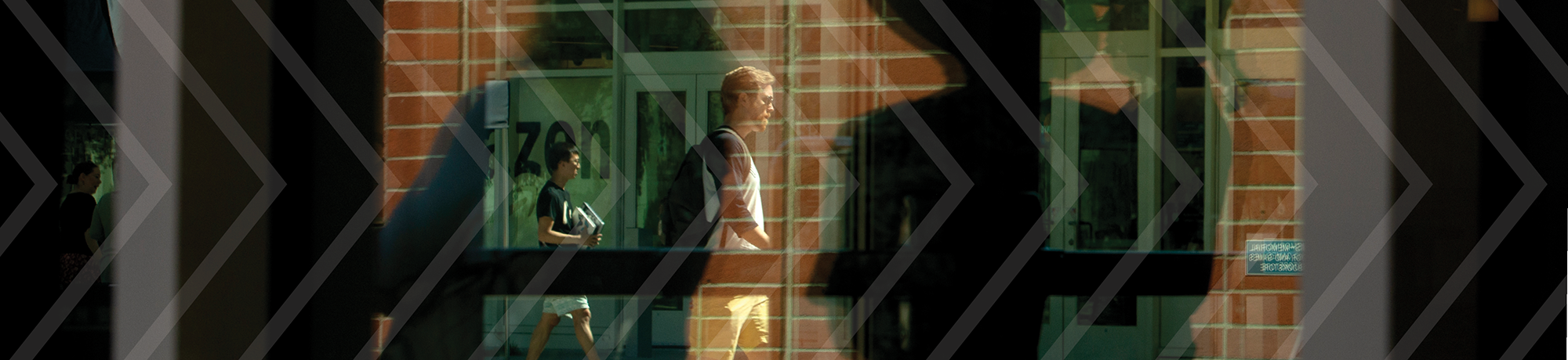 Reflections through glass of students walking on campus