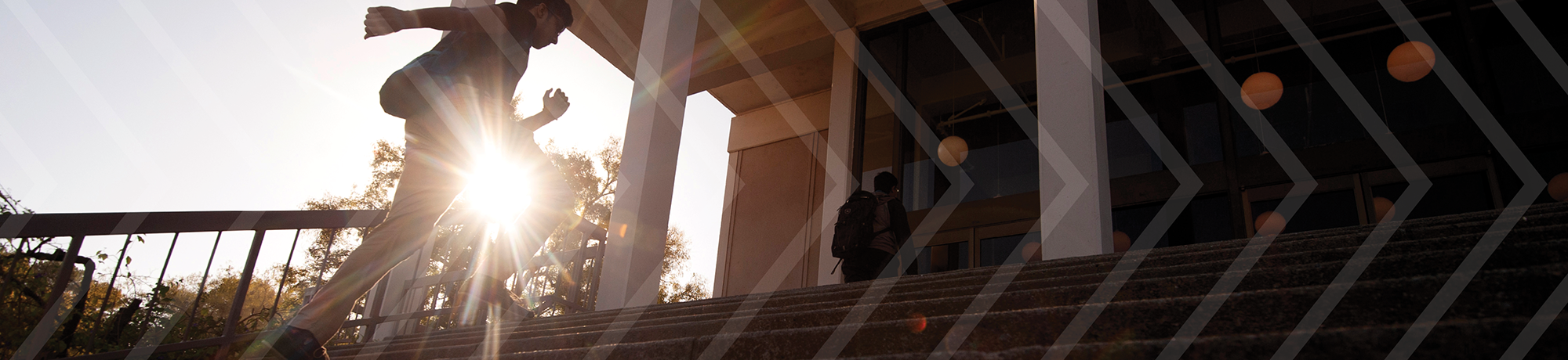 Image of backlit students running up stairs to class